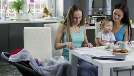 Female-Couple-with-Children-Filling-Documents-at-Home