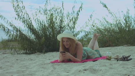 Sonriente-mujer-chateando-en-línea-en-el-teléfono-móvil-en-la-playa