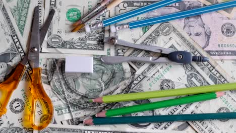 high-school-expenses,-concept,-pencils-on-money,-dollars,-rotating,-turning,-from-above