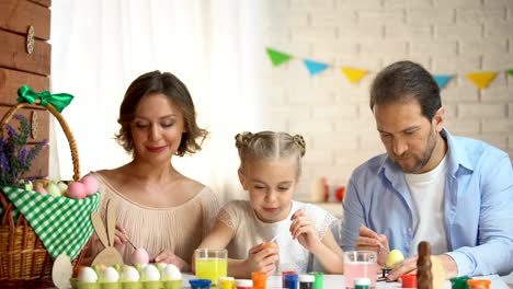 Familia-feliz-mirando-a-cámara-y-sonriendo,-colorear-huevos,-preparación-de-la-Pascua