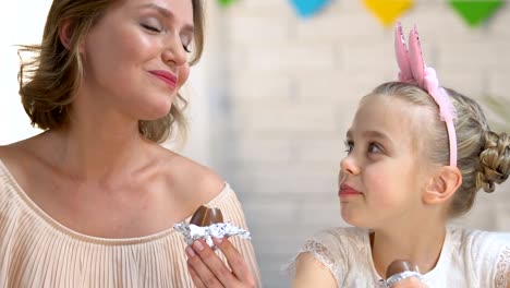 Niedliche-Tochter-und-Mutter-essen-Schokolade-Eier-genießen-Zeitvertreib-zusammen,-Familie