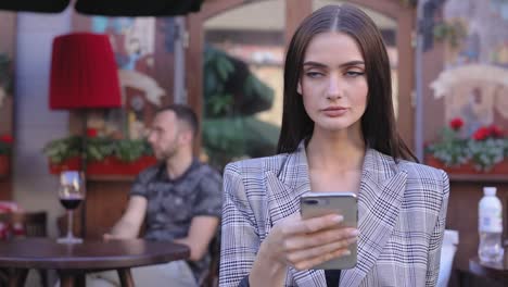 Hermosa-mujer-con-teléfono-móvil-en-el-Cafe-al-aire-libre