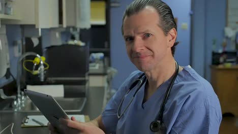 Male-nurse,-doctor,-or-surgeon-using-a-tablet-looking-up-and-smiling