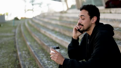 Mann-spricht-am-Telefon-und-trinkt-Kaffee-draußen