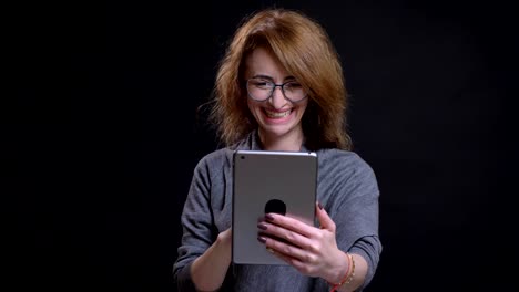 Closeup-portrait-of-attractive-caucasian-middle-aged-woman-having-a-video-call-on-the-tablet-casually-with-the-background-isolated-on-black