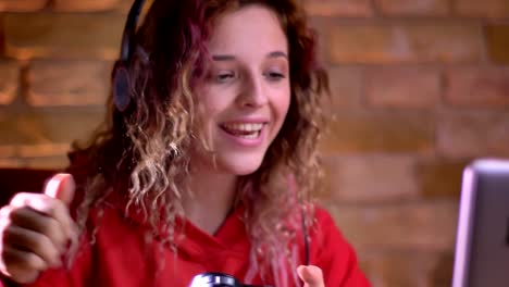 Close-up-portrait-of-young-female-blogger-playing-video-game-using-joystick-and-winning-happily-on-bricken-wall-background.