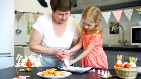 Kleines-Mädchen-mit-Oma-Putting-Cream-auf-Cookies