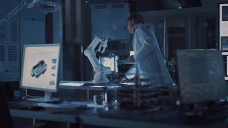 Professional-Heavy-Industry-Robotics-Engineer-Wearing-White-Coat-Holding-Tablet-Computer-Walks-Through-Laboratory.-Facility-Full-of-Computers,-Various-Industrial-Design-Components-and-with-Robotic-Arm