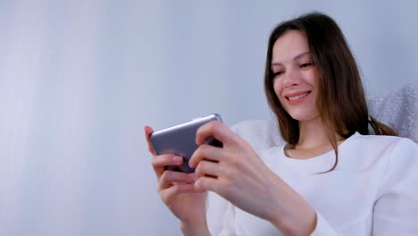 Young-brunette-woman-is-playing-game-on-mobile-phone.