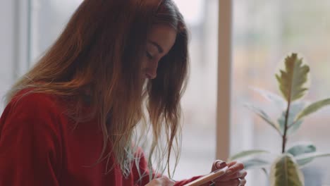 Mujer-sonriente-en-el-café-usando-el-teléfono-móvil-y-enviando-mensajes-de-texto-en-las-redes-sociales,-sentado-solo