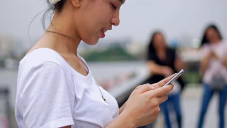 Hermosa-joven-asiática-usando-el-teléfono-inteligente-disfrutando-de-la-lectura-de-medios-sociales.