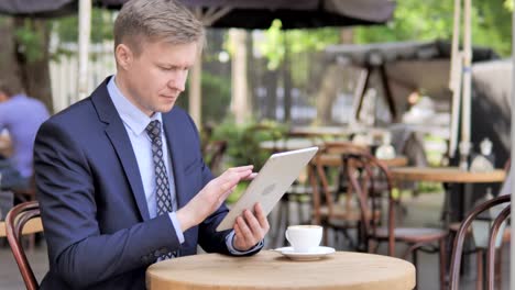 Geschäftsmann-nutzt-Tablet,-Sitting-im-Außencafé