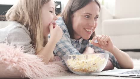 Mutter-mit-Tochter,-die-Popcorn-isst,-während-sie-Film-sieht