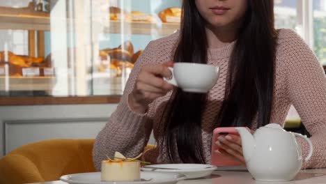 Unrecognizable-woman-using-smart-phone-while-drinking-hot-tea-at-the-coffee-shop