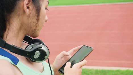 Lifestyle-asiatische-Sportfrauen-halten-Smartphone-spielen-Musik-Entspannung