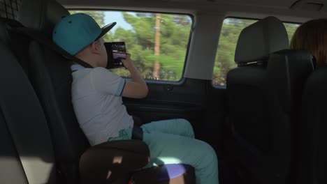 Boy-taking-pictures-with-cell-when-traveling-by-car