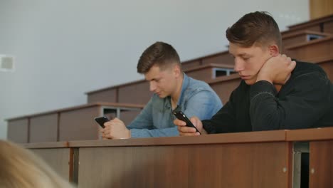 Multi-Ethnische-Gruppe-von-Studenten-mit-Smartphones-während-der-Vorlesung.-Junge-Menschen,-die-soziale-Medien-während-des-Studiums-an-der-Universität-nutzen.