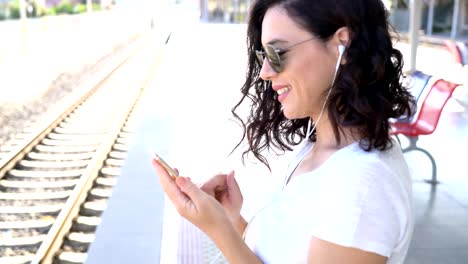 The-girl-is-waiting-for-the-train-at-the-subway-station-and-listening-to-music-on-headphones.-Use-smartphone-in-the-subway.-Underground.-Student-rides-the-subway.