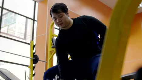 Asian-man-trying-to-exercise-with-dumbbell-in-fitness-gym,-Healthy-lifestyle,-weight-loss-desire