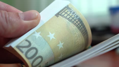 Fingers-sorting-through-a-stack-of-banknotes.-A-stack-of-notes-for-200-euros.-Close-up.-Counterfeit-money.