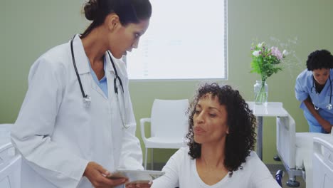 Front-view-of-African-american-female-doctor-discussing-medical-report-with-disabled-female-patient