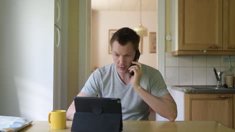 Junge-glückliche-Mann-mit-digitalen-Tablet-und-Telefon-durch-das-Fenster