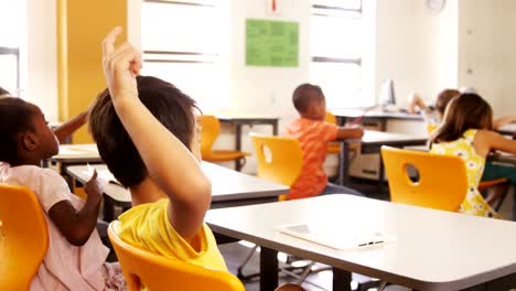 School-kids-raising-hand-in-classroom