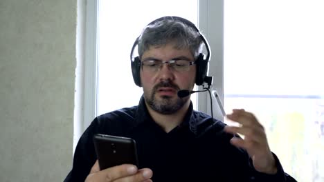 Un-hombre-con-gafas-y-auriculares.-Hablar-por-teléfono