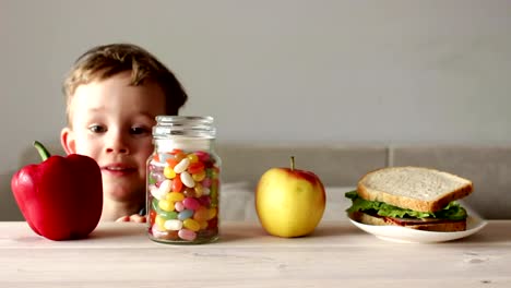 niedliche-kleine-Junge-mit-Glas-mit-bunten-Süßigkeiten