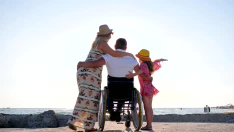 behinderter-Mann-mit-Frau-und-Tochter-auf-Hintergrund-Meer