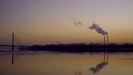 The-smoky-plant-on-the-background-of-the-river-and-the-setting-sun