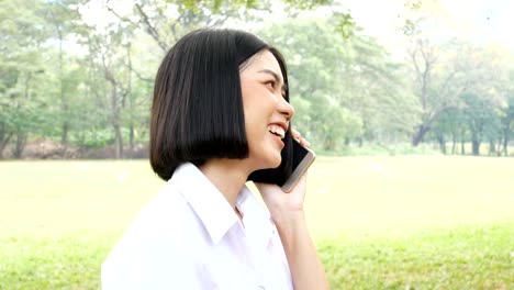 Asian-woman-using-smartphone-at-outdoor-park.-People-lifestyle-concept.