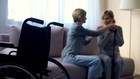 Caring-daughter-talking-with-disabled-senior-mother-at-home,-rehabilitation