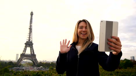 Mujer-alegre-hacer-video-llamada-por-tablet-con-el-fondo-de-la-Torre-Eiffel-en-cámara-lenta