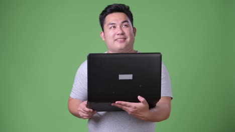 Young-handsome-overweight-Asian-man-against-green-background