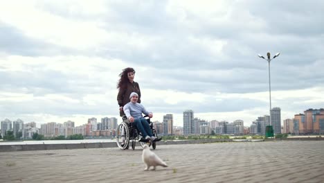 Hombre-discapacitado-en-silla-de-ruedas-con-mujer-joven-jugando-con-una-paloma