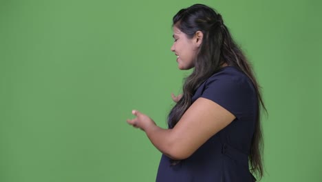 Young-overweight-beautiful-Indian-businesswoman-against-green-background