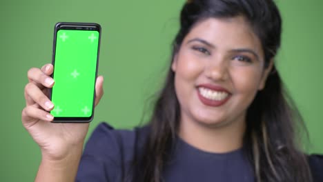 Young-overweight-beautiful-Indian-businesswoman-against-green-background