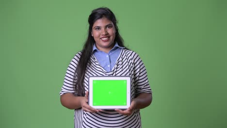 Young-overweight-beautiful-Indian-businesswoman-against-green-background