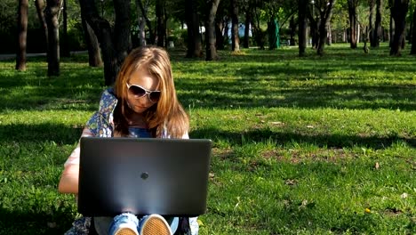 Chica-en-un-día-soleado-en-un-parque-con-un-ordenador-portátil