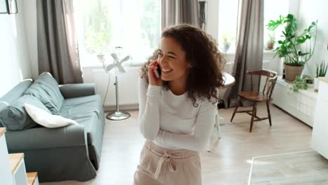 Encantadora-mujer-joven-usando-el-teléfono-en-moderno-apartamento-elegante.