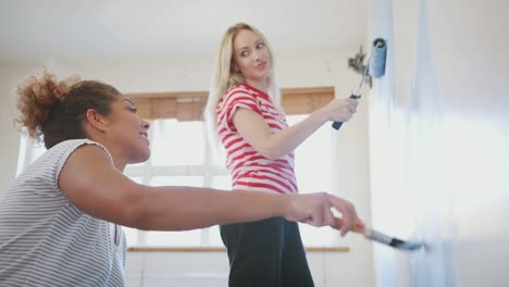 Dos-mujeres-decoración-de-habitación-en-nuevo-hogar-pintura-pared-juntos