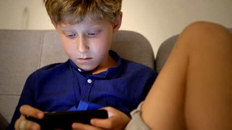 Little-boy-playing-the-online-game-using-the-mobile-smartphone-gadget-device