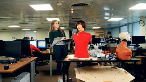 Lady-with-a-laptop-is-observing-a-talking-female-mannequin