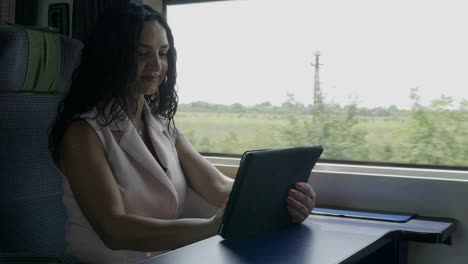 Attractive-cheerful-passenger-woman-enjoying-trip-chatting-on-social-networks-using-tablet-pc-while-she-travel-alone