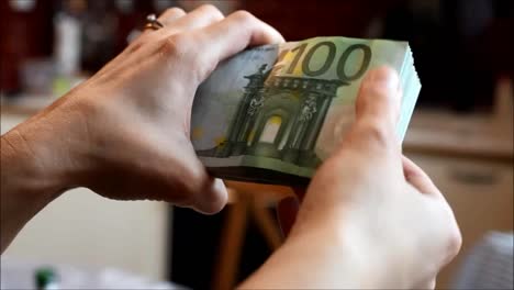 hands-handling-a-wad-of-hundred-euro-bills.