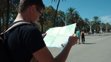 Man-is-examining-map-of-city-transport,-looking-around-on-street