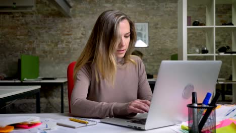 Closeup-of-beautiful-adult-woman-typing-on-the-laptop-in-office-and-smiling