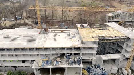 Construcción-de-un-edificio-de-gran-altura,-una-vista-desde-la-parte-superior-con-un-Dron.-Los-obreros-construyen-una-casa.-Panorama-desde-la-parte-superior-de-la-obra