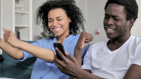 African-Couple-Celebrating-Success-on-Smartphone